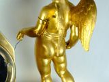 a gold statue of an angel with a clock in front of it