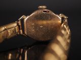 a close up of a gold wrist watch on a black surface