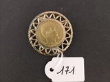 a gold coin with a tag attached to it on a black surface