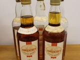 three bottles of whisky sitting on top of a wooden table