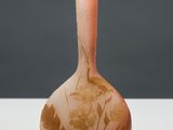 an orange vase sitting on top of a white table next to a gray wall
