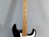 an electric guitar sitting on top of a white table next to a black guitar