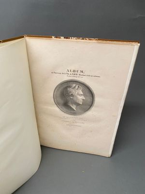 un livre ouvert posé sur une table, à côté d'une pièce de monnaie