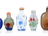 plusieurs vases en verre de différentes couleurs sont alignés sur une surface blanche