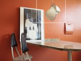 une table et des chaises dans une pièce où est accrochée une horloge au mur