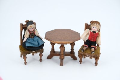 two dolls that are sitting at a table and chairs