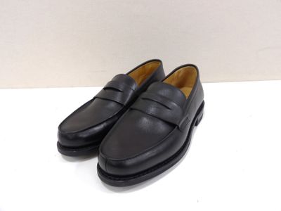 une paire de mocassins noirs posés sur une surface blanche