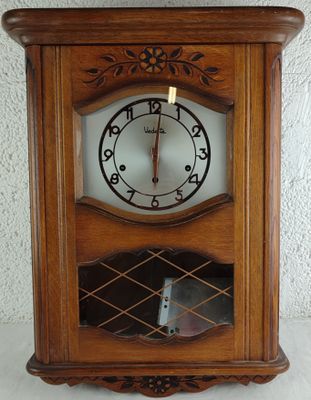 une horloge posée sur une étagère, elle-même posée sur une table