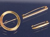 deux broches en or et une épingle sur un fond bleu
