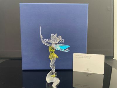 La figurine est posée sur une table, à côté d'une boîte bleue.