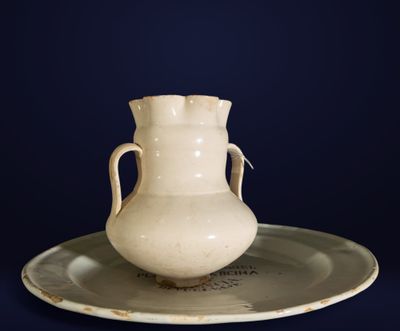 un vase blanc posé sur une assiette à fond bleu