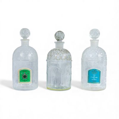 trois bouteilles vides posées les unes à côté des autres sur une surface blanche