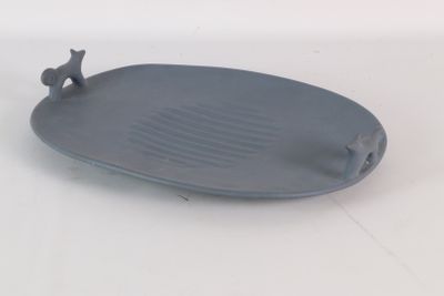 une assiette grise ornée d'un oiseau, posée sur un fond blanc