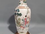 a white vase with a gold base and a painting on it