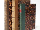 three old books are stacked on top of each other on a white surface