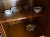 a wooden cabinet with bowls and cups on it
