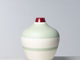 un vase vert et blanc posé sur une table blanche