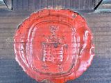 a red wax seal on a wooden cross on a wall