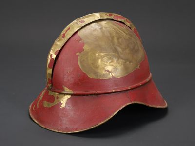 un vieux casque rouge et or sur fond noir