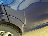a close up of a blue car with a denting on it