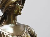 bronze statue of a woman holding a tennis racquet and a tennis ball