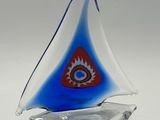 a small glass sailboat with a red eye on it