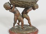 statue en bronze représentant deux enfants portant un panier, posée sur un socle en bois