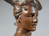 bronze bust of a woman with a hat on her head