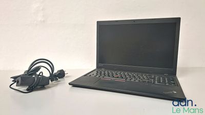 un ordinateur portable posé sur une table et auquel est relié un chargeur