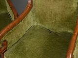 pair of green velveted armchairs with carved wood arms