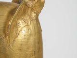 a gold vase that has a bird on top of it