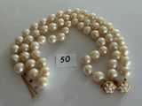 two strands of white pearls with gold clasps on a white surface