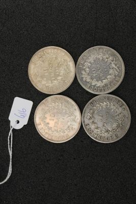 four silver coins and a tag on a black surface