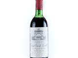 a bottle of red wine sitting on top of a white table