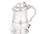 une chope ancienne en métal argenté, munie d'une anse en corde, sur fond blanc