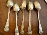 six spoons are lined up on a wooden table