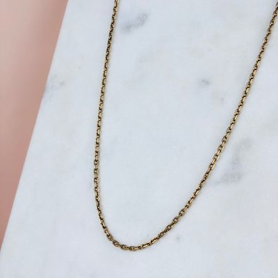 un collier à chaîne en or posé sur une surface en marbre