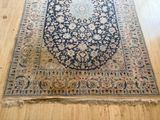 un tapis posé à même le sol dans une pièce dotée d'un parquet et d'un mur en bois