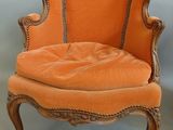 an orange chair sitting on top of a wooden floor next to a white wall