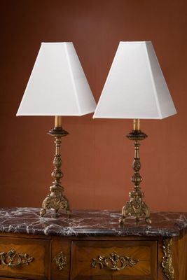 deux lampes posées sur une commode dans une pièce aux murs marron