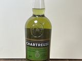 La bouteille de Chartreuse est posée sur une table en bois.