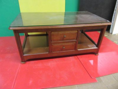 a coffee table with a glass top on a red mat