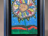 a painting of a flower in a blue frame on a table