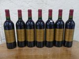 six bouteilles de vin rouge alignées sur une table en bois