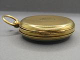 a close up of a gold pocket watch on a gray surface