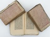 three old books are stacked on top of each other on a white surface
