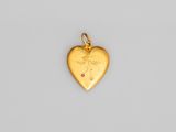 un pendentif en forme de cœur en or orné d'une petite pierre rouge