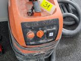 an orange machine that is sitting on the floor next to a wall