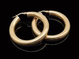une paire de boucles d'oreilles en or sur une surface noire