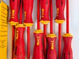 six red and yellow screwdrivers are lined up next to a yellow box